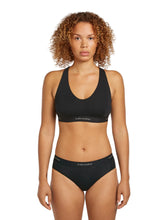Woman wearing a black Icebreaker Sprite Racerback Bra on a white background