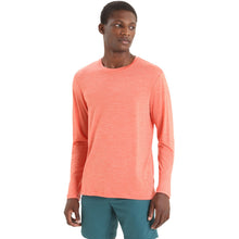 A man wearing a heather coral long-sleeve crewneck shirt and teal shorts, standing against a plain white background.