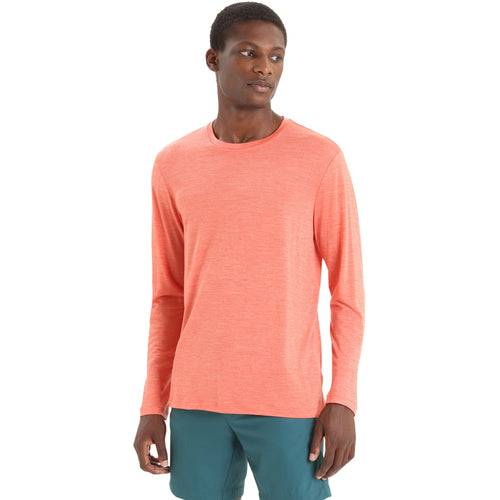 A man wearing a heather coral long-sleeve crewneck shirt and teal shorts, standing against a plain white background.