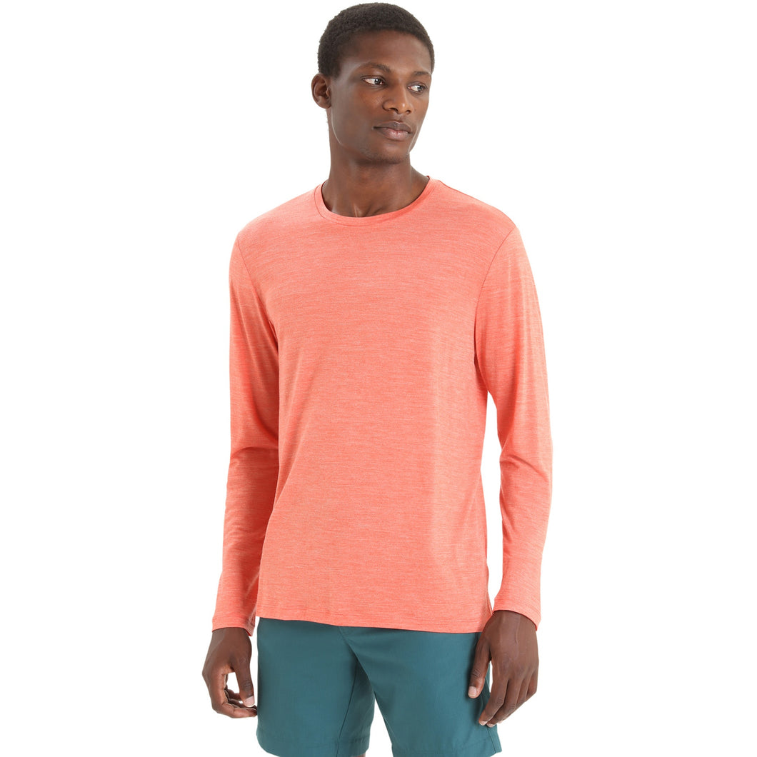 A man wearing a heather coral long-sleeve crewneck shirt and teal shorts, standing against a plain white background.