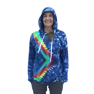 A person wearing a tie-dye hoodie with a hood, standing against a plain wall.